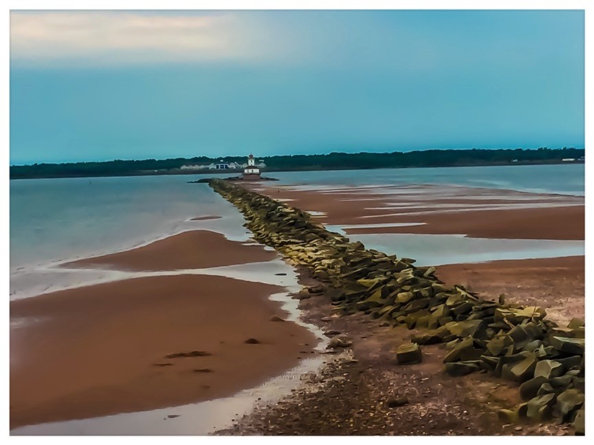 Red sand beach at low tide with lighthouse in distance