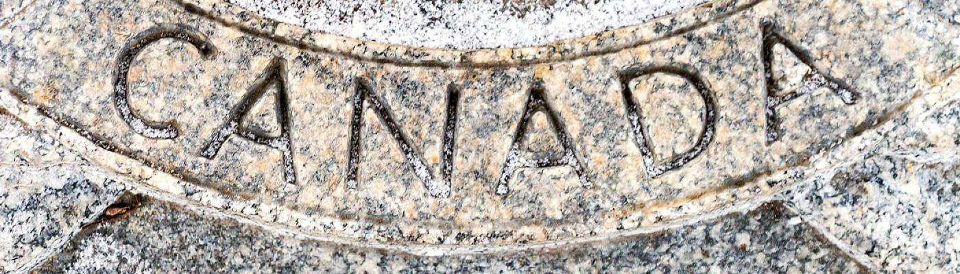 The word Canada etched into marble stone