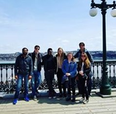 Group of young people standing in front of iron fence bordering St. Lawrence River