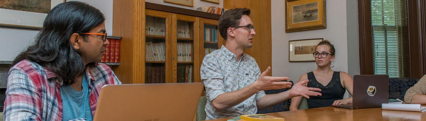 Students sitting around a table discussing books in seminar
