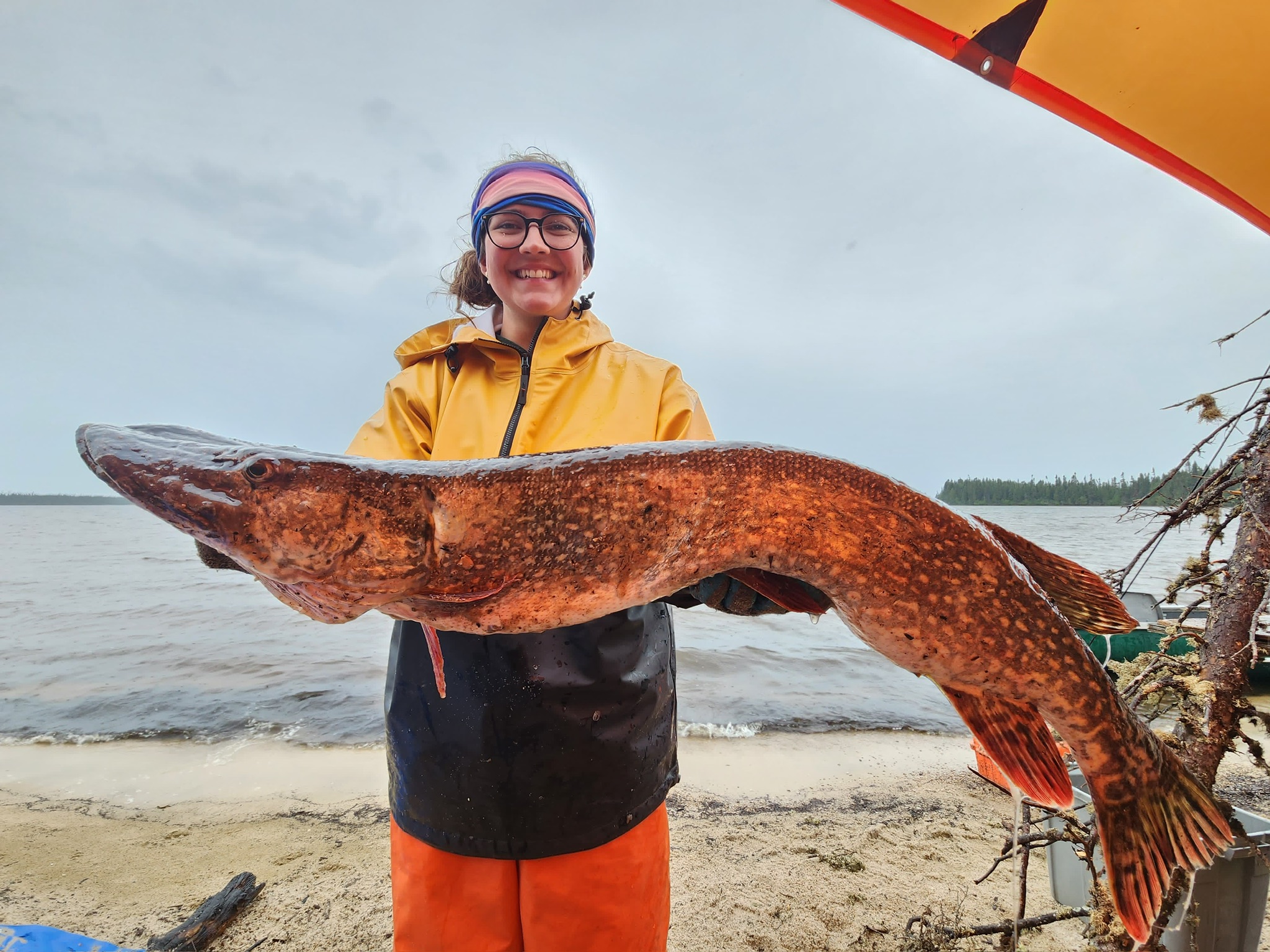 Student smiling holding a fish during her work term at the Ministry of Natural Resources & Forestry.