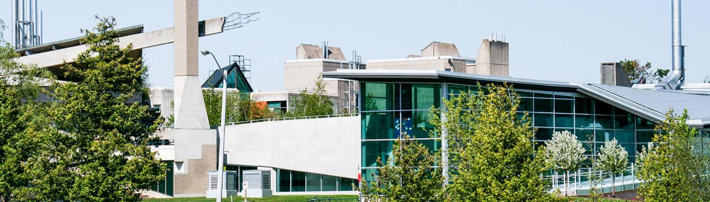 Exterior view of the Chemical Sciences Building from across the Otonabee river in the summer afternoon sun