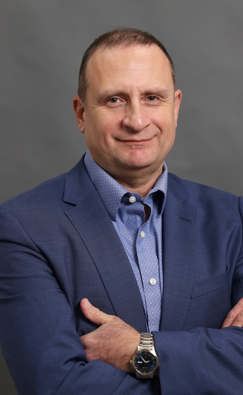Prof. Genkin in blue suit looking at camera with arms folded