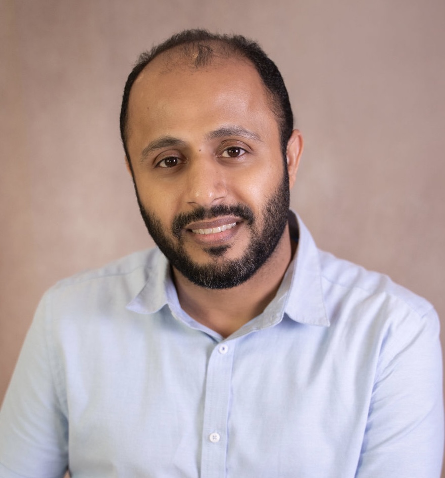 Prof. Ghaleb in blue dress shirt looking at camera