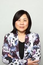 Wenying Feng wearing a purple and white blazer with her arms crossed facing the camera