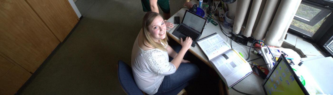 A girl working on her computer in her dorm room at Trent