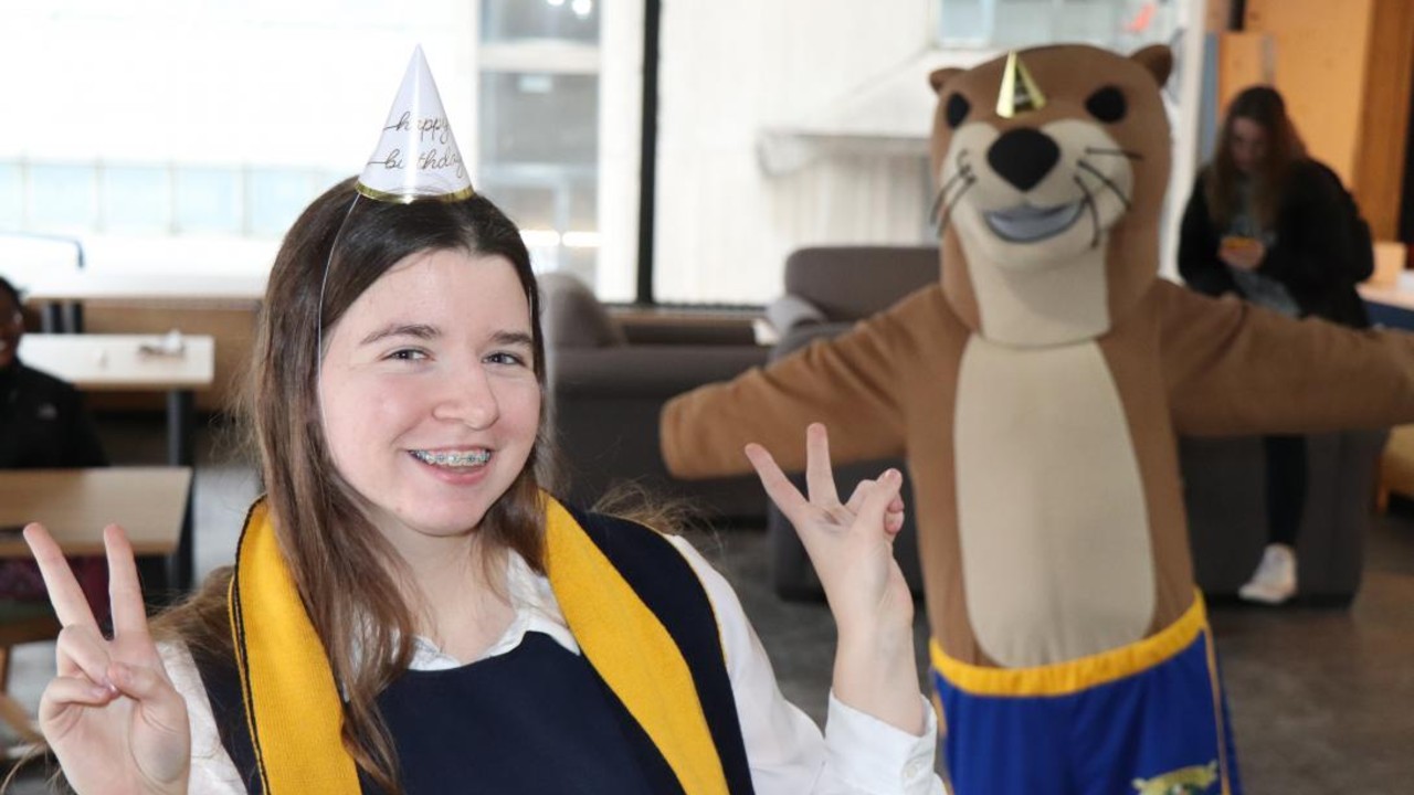 A student posing with Ottie the Otter