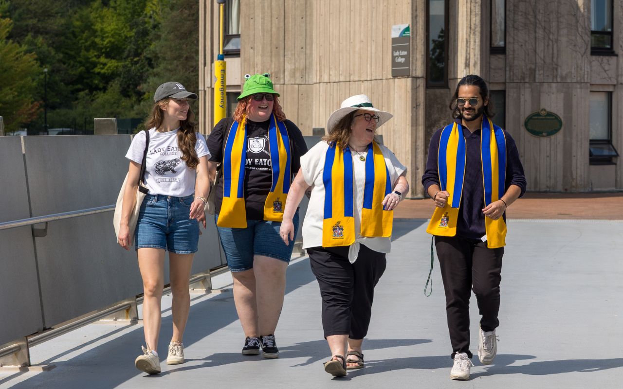 Photo of four students walking across bridge