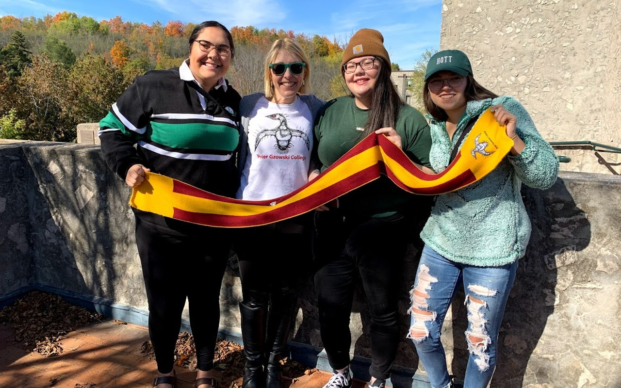 Gzowski principal Melanie Buddle and several students holding up a college scarf.