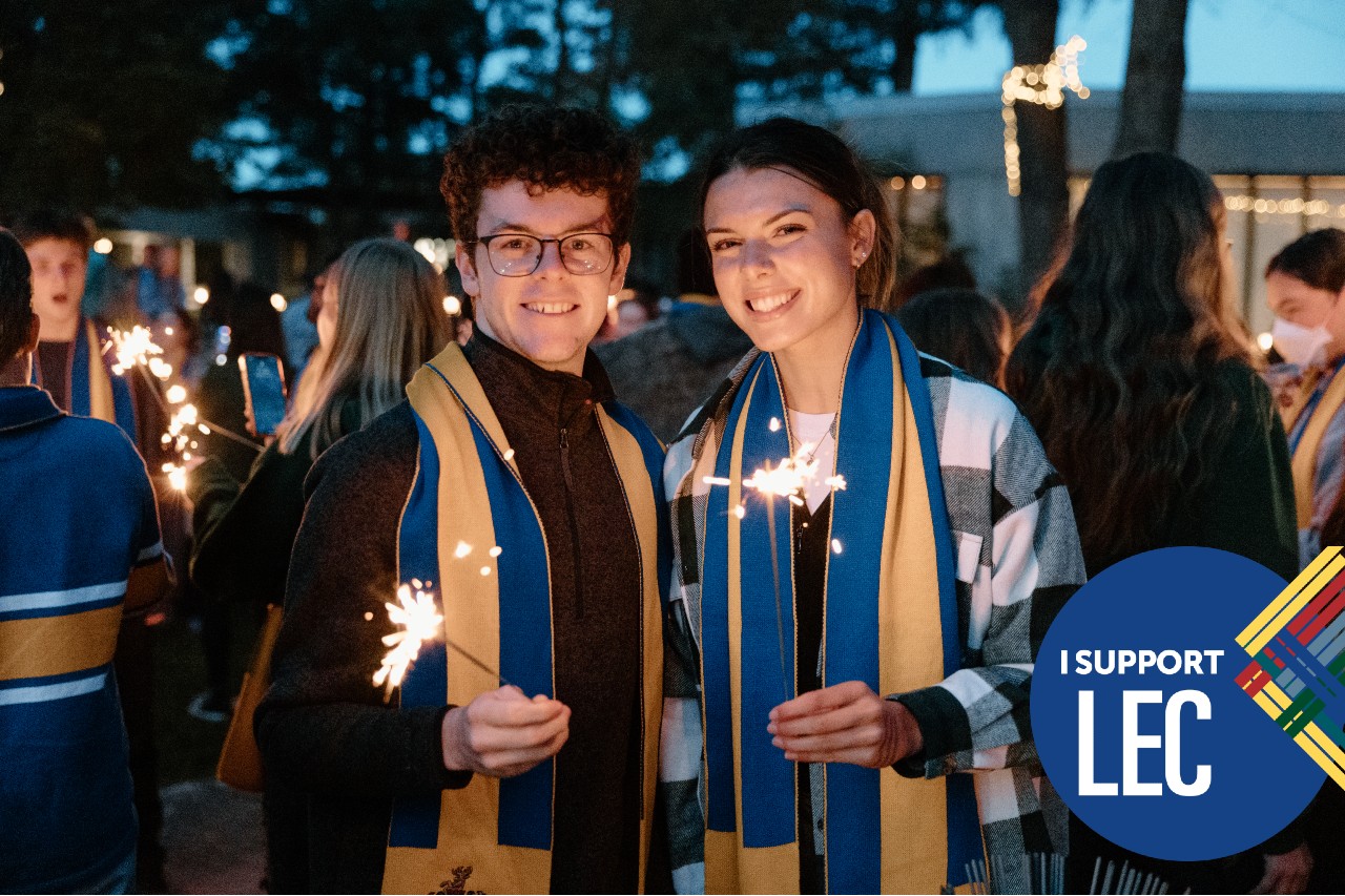 Two students holding sparklers at a Lady Eaton College evening event. An overlaid graphic says I Support LEC.