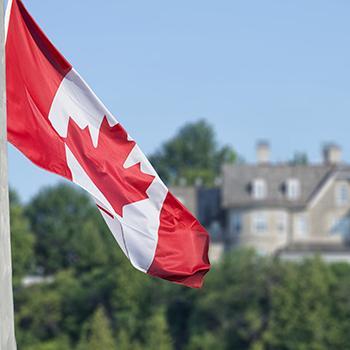 The Canadian flag waving in front of a building