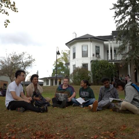 A group of students sitting on the lawn outside Traill College
