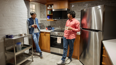Photo of two students drinking coffee in kitchen