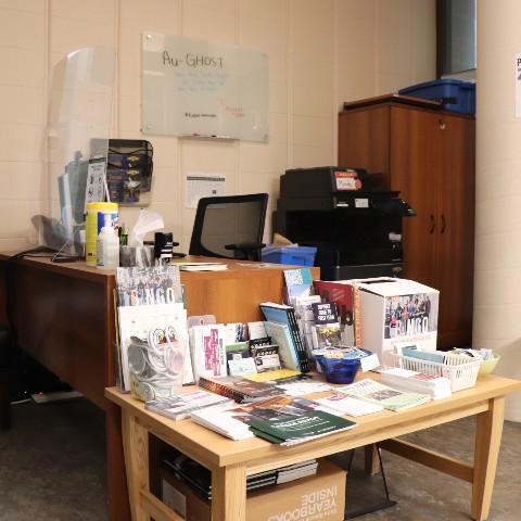 A desk and display of reading material inside the Otonabee College Office