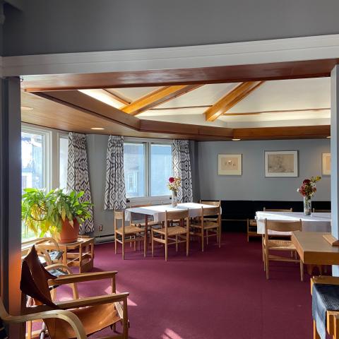 The Senior Common Room at Traill College. It is decorated in a 60s style with exposed wood beams along the ceiling, large windows, and vintage wooden furniture.