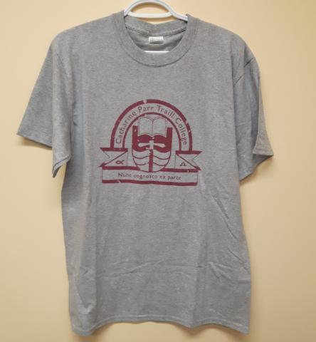 A grey tee shirt with a maroon Traill College logo in the centre.