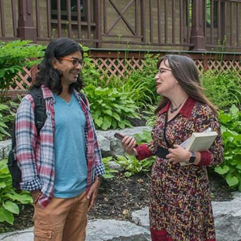 A professor speaking to a graduate student outside Kerr House at Traill College