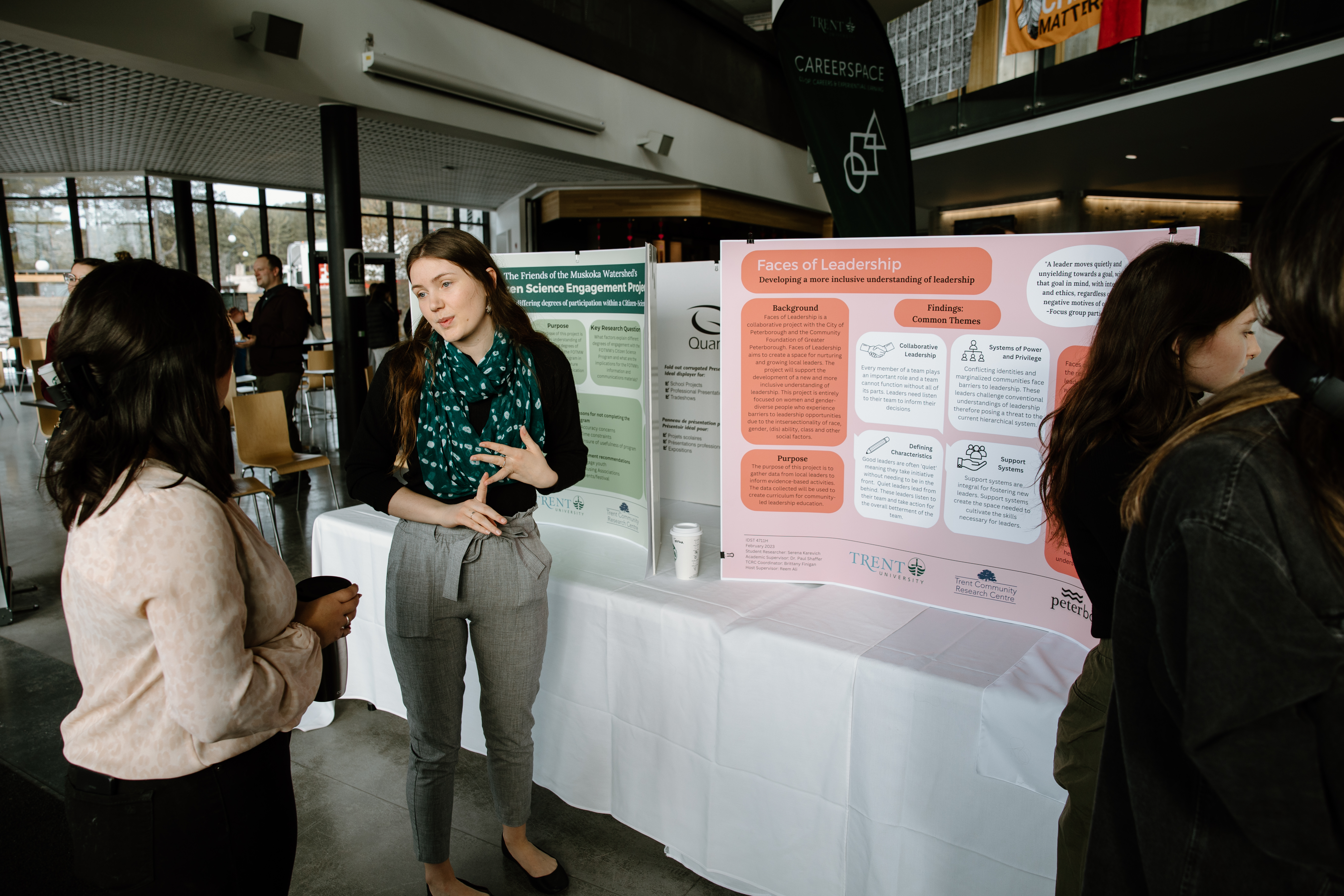 Student talking to a group with a research poster behind them