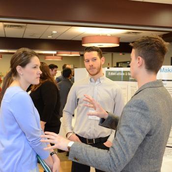 Student community-based researchers talking in front of their poster at the Celebration of Research.