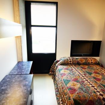 A gzowski college bedroom with a window, desk and dresser