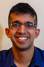 Jeet Adhvaryu smiling at the camera against a beige wall