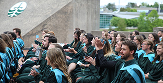 Students sitting on the podium clapping during their convocation ceremony