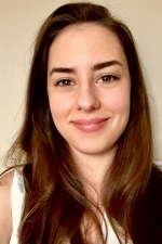 Olivia Williams smiling at the camera against a beige wall