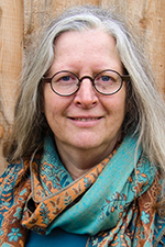 Bridgitte Evering smiling at the camera against a wooden wall