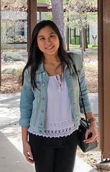 Wai Shi Pang smiling at the camera, on a covered walkway with a few trees in the background