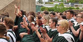 Student in gowns clapping on the stage.