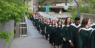 Students in gowns processing across Stevenson Bridge.