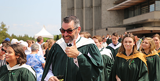 Graduate giving thumbs-up in procession