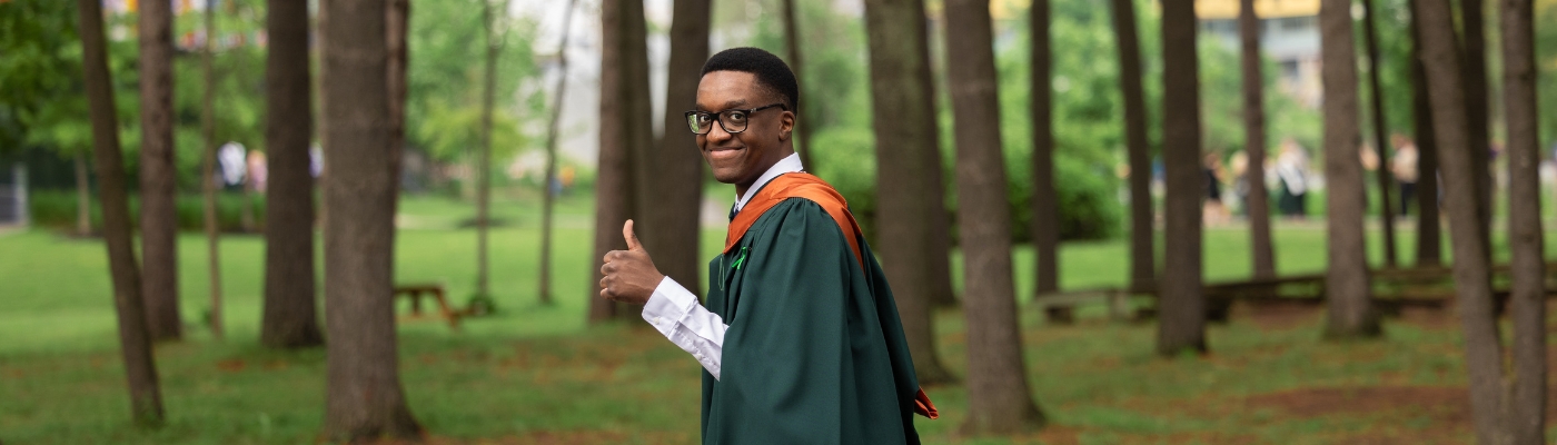 A man smiling at the camera giving a thumbs up