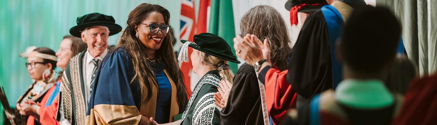 A convocation ceremony with people on stage, smiling