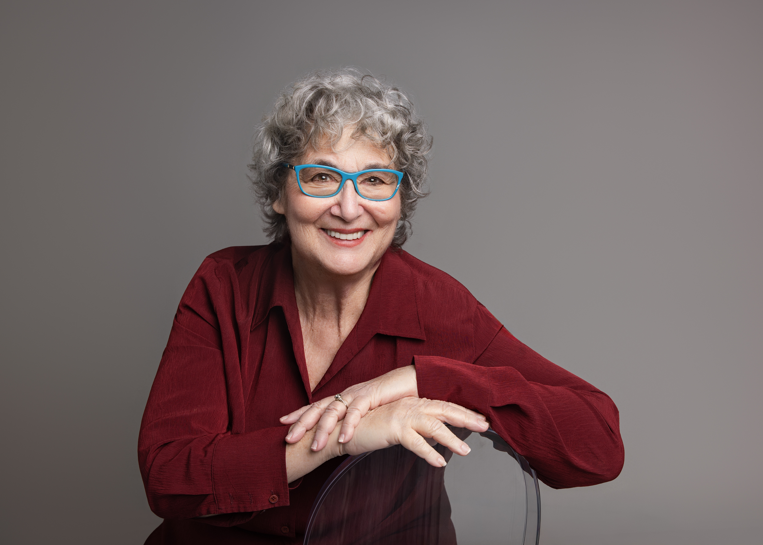 A woman sitting backwards on a chair, smiling at the camera