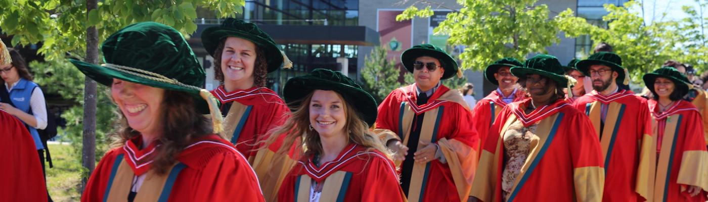 A group of graduating students walking and smiling at Trent