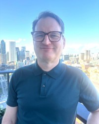 James Penney standing on a balcony with tall buildings in the background