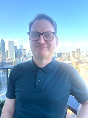 image of James standing on a balcony with large city buildings in the background
