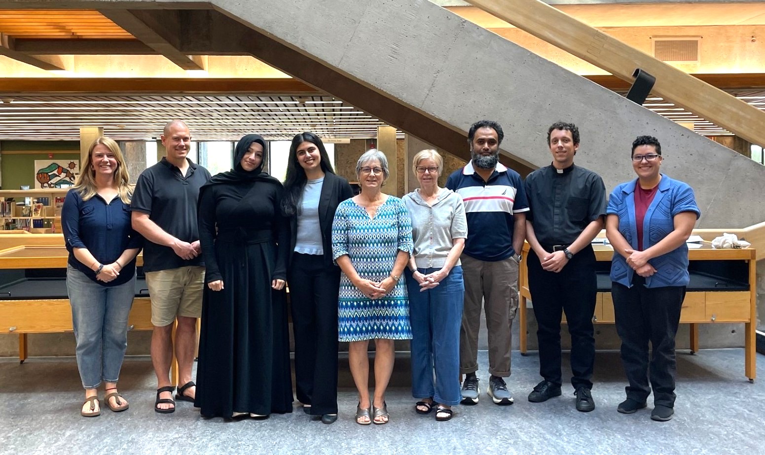 A group of people smiling and looking at the camera in front of a flight of stairs in the Bata Library