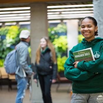 Student in bata library wearing Trent Green Sweater with students in background. 
