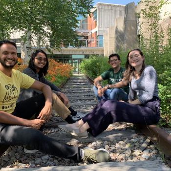 Four international students sitting on the old train tracks at the Peterborough campus