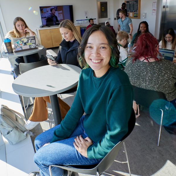 A student smiling the common room of a residence floor