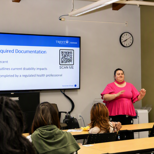 A lecturer give a talk in front of a screen with students listening