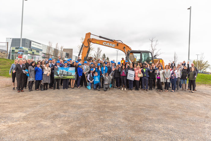 Dignitaries and students pose for a group photo in front of a tractor at the Trent University Durham GTA expansion groundbreaking ceremony.