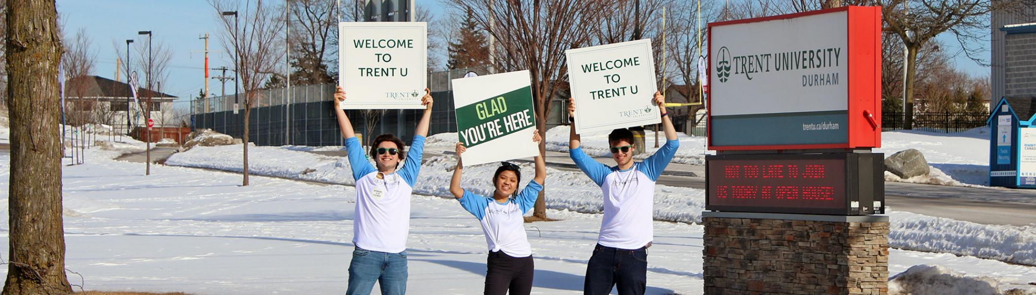 Trent University Durham students holding up welcome signs outside of the campus open house event.