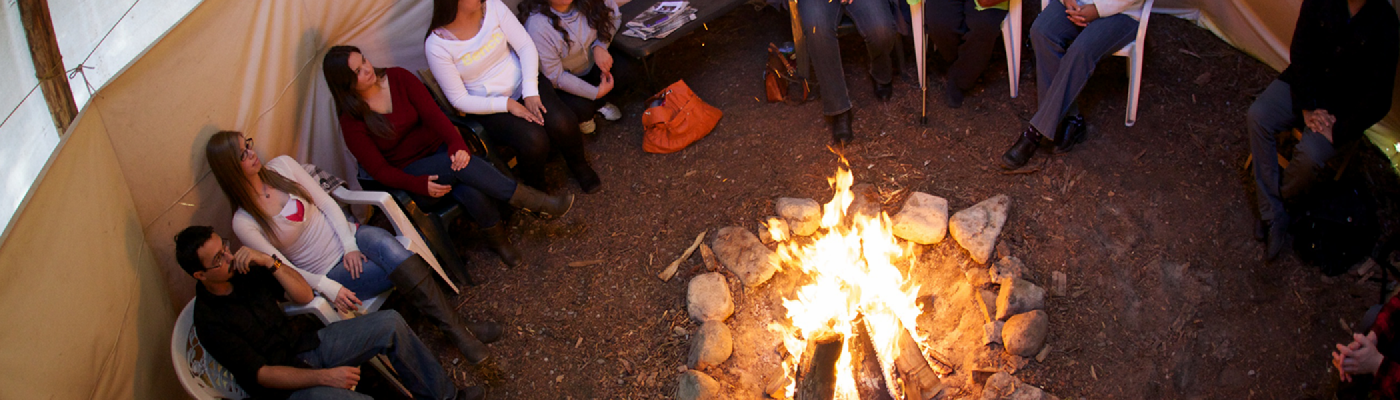 People sitting in a tipi with a fire lit