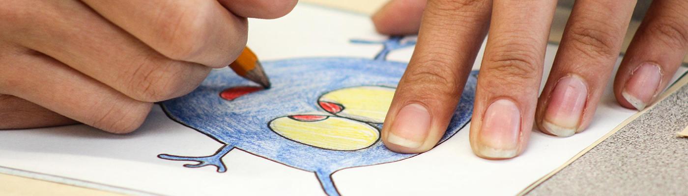 Closeup of a woman's hands colouring in an iluustration on a table