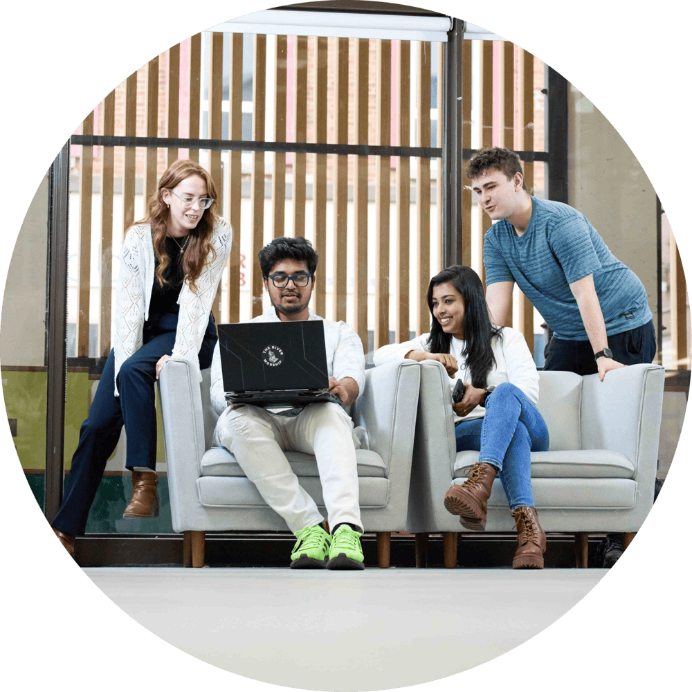 Four students sitting on couches, one of them is on a laptop