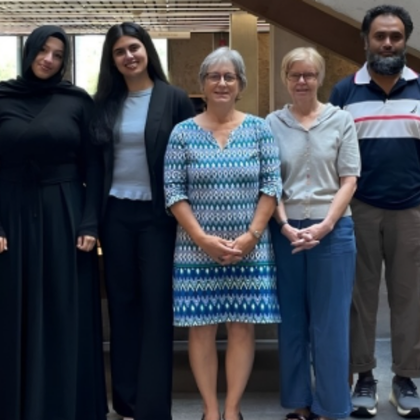 Group photo of members of the 2026-2027 Multifaith Network standing side by side indoors. Five individuals are visible, facing the camera, with a dark blue background behind them.