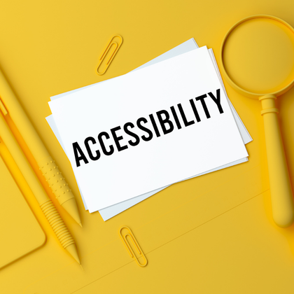 A white card with the word “ACCESSIBILITY” printed in bold black letters is placed on a bright yellow surface.